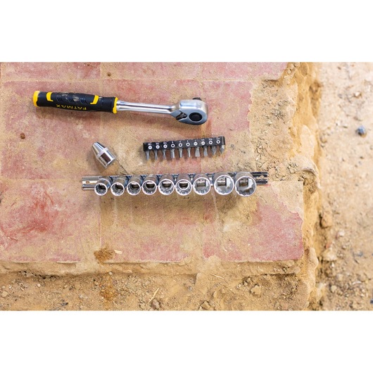 STANLEY FMMT82679-0 ratchet wrench and socket set with bits, top view on outdoor stone surface.