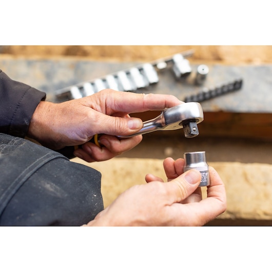 Photo of STANLEY FMMT82681-0 socket wrench with hand attaching socket, close-up view, workshop setting.