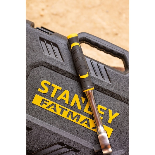 STANLEY FATMAX FMMT82684-1 ratchet with black and yellow handle resting on textured toolbox, angled view.