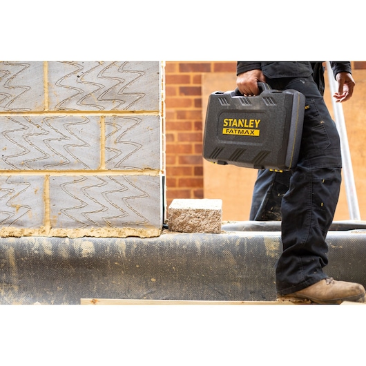 Stanley FMMT82684-1 FATMAX hard tool case carried by worker at construction site.