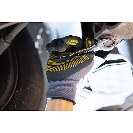 STANLEY FMMT82900-0 wrench in gloved hand tightening bolt, close-up photo during automotive repair.