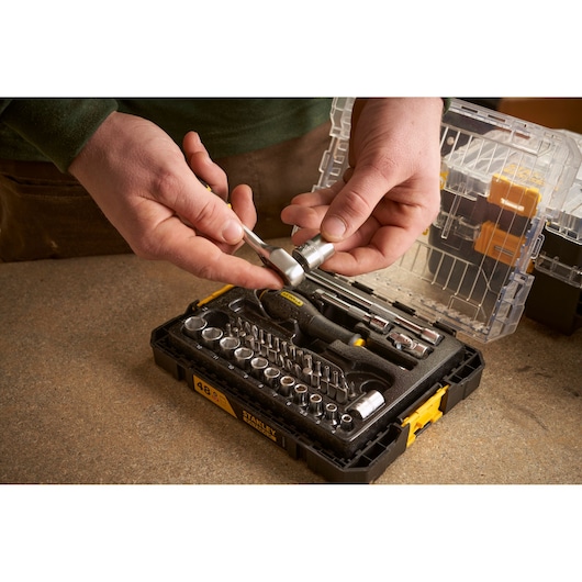 STANLEY FMMT98101-0 socket and ratchet set photographed in use, with black case open on workbench.