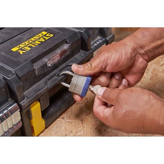 Photo of STANLEY FMST1-71966 toolbox locked with a padlock and key being inserted, close-up view.