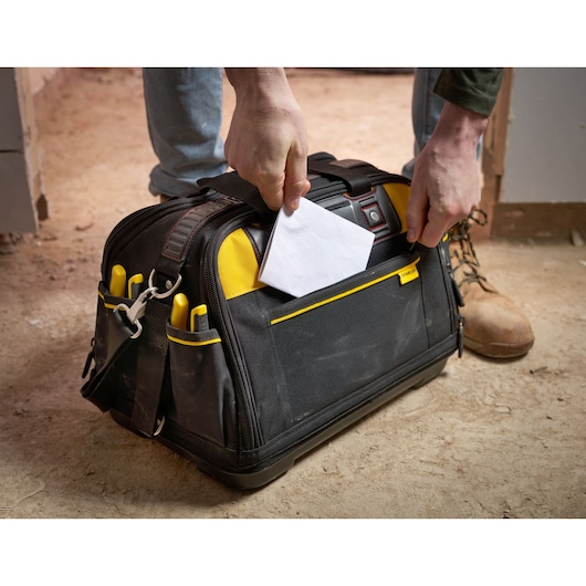 STANLEY FMST1-73607 tool bag with yellow accents and front pocket, photographed on a construction site.