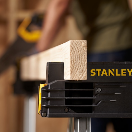 Photo of STANLEY FMST1-75763 sawhorse holding a wood plank, close-up view with logo visible.