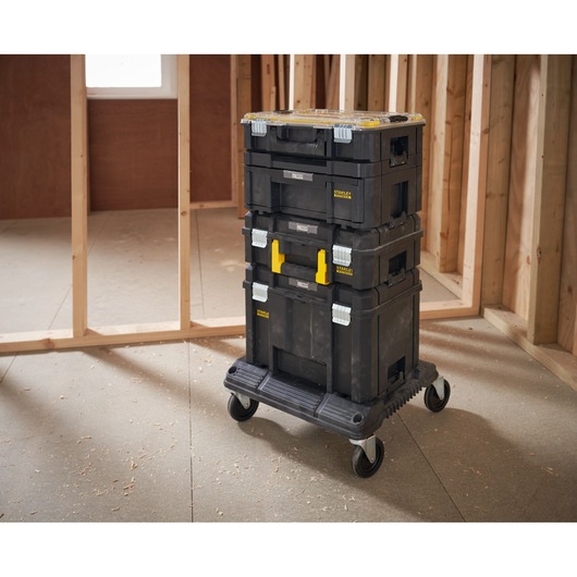 STANLEY FMST1-80107 stackable tool storage boxes with wheels, black, shown in a construction setting.