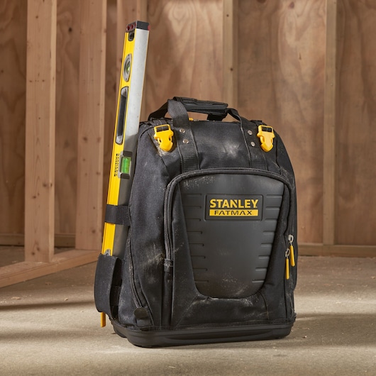 STANLEY FMST1-80144 tool backpack with yellow level attached, shown on construction site floor.