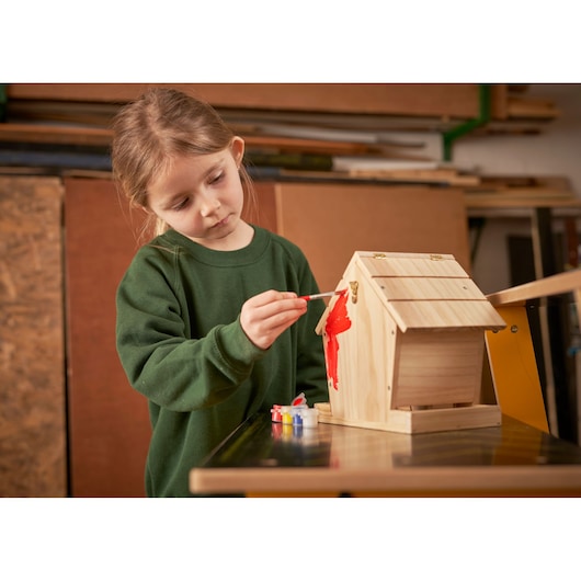 STANLEY K020-SY photography of child painting wooden birdhouse with red paint at table.