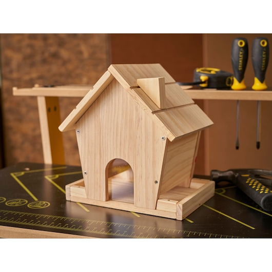 STANLEY K020-SY wooden birdhouse on workbench, surrounded by STANLEY screwdrivers and measuring tape.