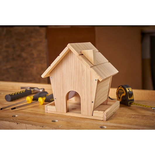 STANLEY K020-SY wooden birdhouse on workbench with tape measure and screwdrivers.