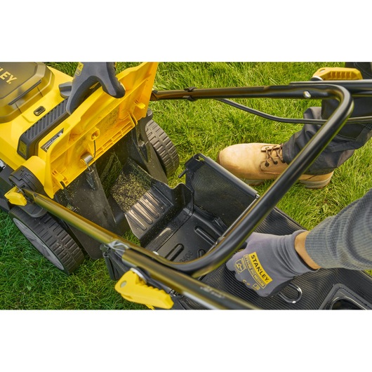 STANLEY SCMWP3401M1-XE lawn mower photo, close-up of grass catcher attachment on green lawn.