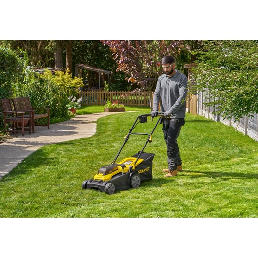 Photo of STANLEY SCMWP3701M2 lawn mower in use on a green lawn, outdoor garden setting.