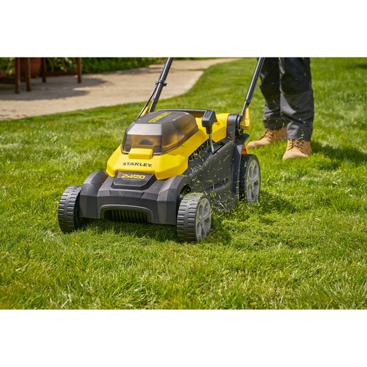 Photo of STANLEY SCMWP3701M2 lawn mower on grass, yellow and black cordless model with person mowing.