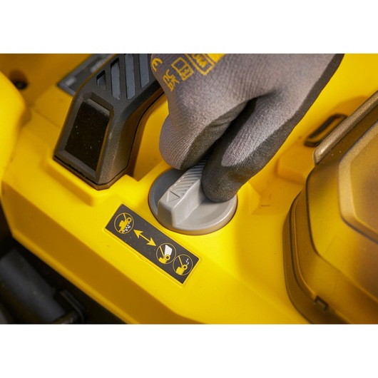 STANLEY SCMWP3701M2 lawn mower control knob close-up, yellow surface, gloved hand adjusting