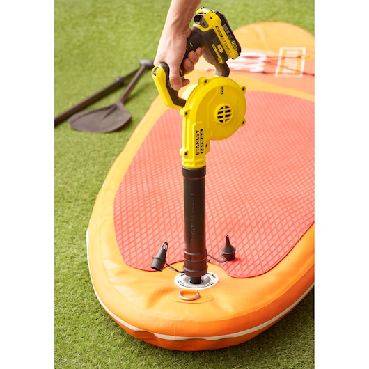 STANLEY SFMCBL01B blower inflating orange paddleboard, grass background, close-up angle.