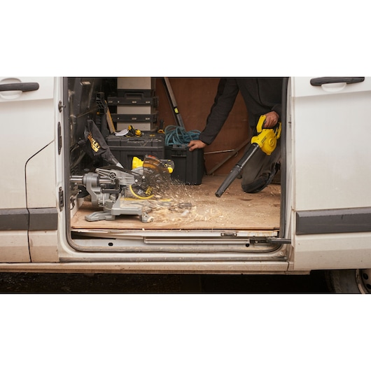 STANLEY SFMCBL01B blower used to clean wood dust inside van workshop with tools and equipment visible.