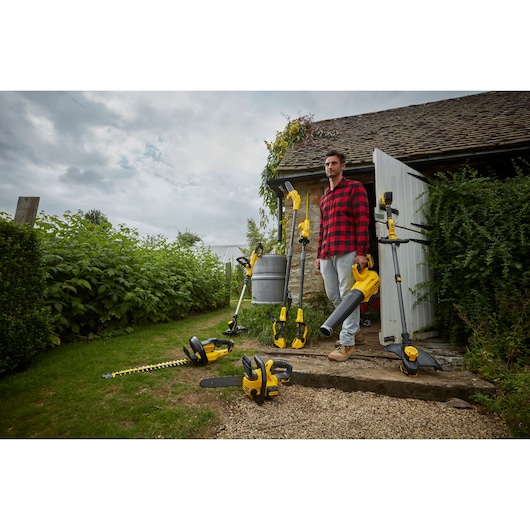STANLEY SFMCCS630M1 garden power tool set, including hedge trimmer, chainsaw, leaf blower, and strimmer, outdoor scene.