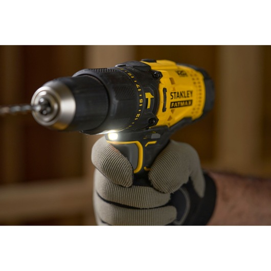 STANLEY SFMCD711D11 yellow and black cordless drill held in gloved hand, close-up side angle.