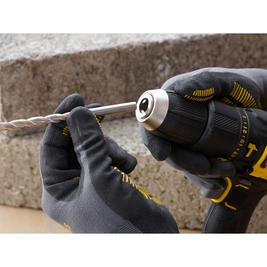 STANLEY SFMCD711D21 cordless drill, close-up side view, gloved hands inserting drill bit.