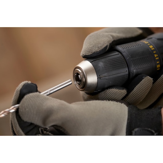 STANLEY SFMCD711D21 cordless drill close-up held by gloved hands, inserting drill bit.