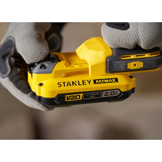 STANLEY SFMCD711D21 V20 Fatmax 2.0Ah lithium-ion battery in gloved hand, close-up side view.