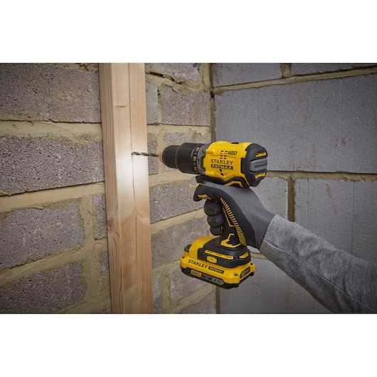 Photo of STANLEY SFMCD715D2K cordless drill in use, yellow and black, drilling into wood.