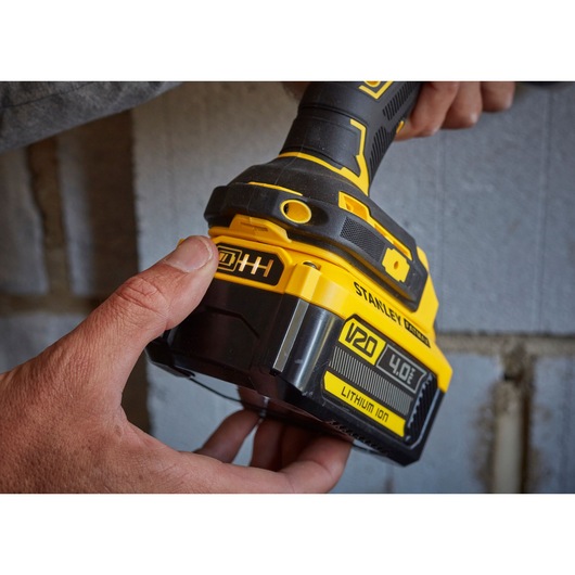 Photo of STANLEY SFMCD715M2K cordless drill with V20 4.0Ah lithium-ion battery being held near a wall.