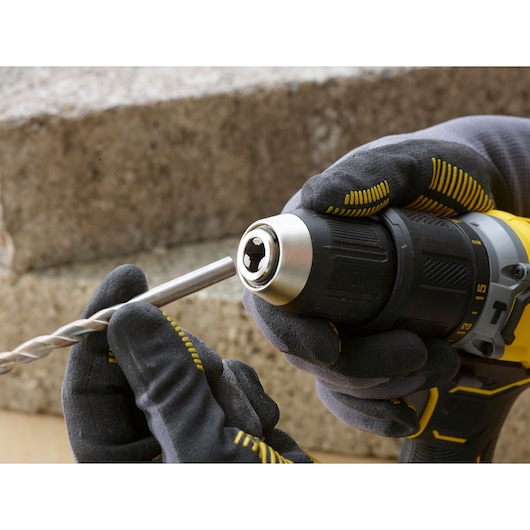 STANLEY SFMCD715M2K drill held by gloved hands, inserting a drill bit, close-up product photography.