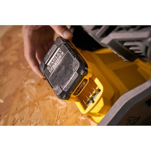 Photo of STANLEY SFMCE001B battery pack being inserted into yellow power tool, close-up view.