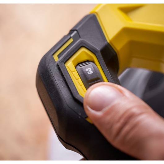 STANLEY SFMCE100D2 tool close-up showing yellow and black speed setting dial with finger adjusting.