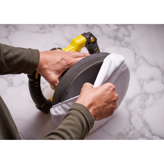 STANLEY SFMCE100D2 cordless polisher held, white pad cover being fitted, close-up photography.