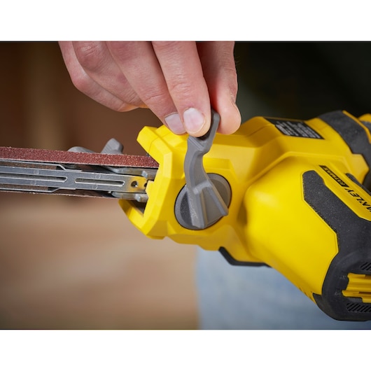 STANLEY SFMCE210B belt sander close-up, yellow body, adjustment lever being used.