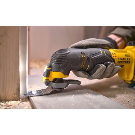 Stanley SFMCE500M1K oscillating multi-tool cutting wood at construction site, close-up view.