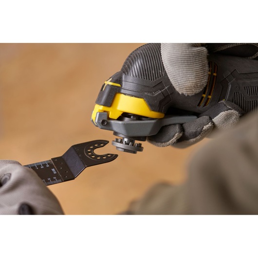 STANLEY SFMCE500M1K oscillating tool close-up with blade attachment held by gloved hands.