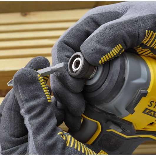 Photo of STANLEY SFMCF810B impact driver close-up, gloved hands inserting a screwdriver bit.