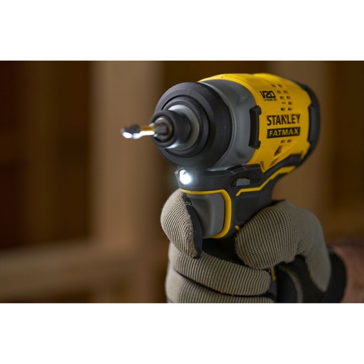 Photo of STANLEY SFMCF810M1K cordless impact driver, yellow and black, held in gloved hand, front view.