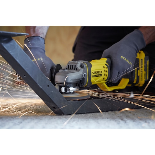 STANLEY SFMCG400M1K angle grinder in use, producing sparks while cutting metal, photography in action.