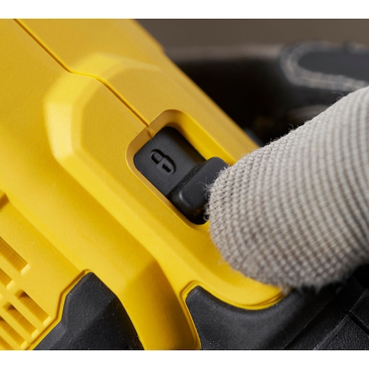 Close-up of STANLEY SFMCG400M1K safety lock switch with gloved hand, photography of power tool detail.