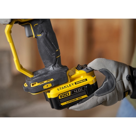 Photo of STANLEY SFMCG400M1K V20 cordless tool handle and battery, yellow and black, held by gloved hand.