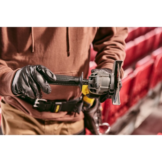 Stanley SFMCG700M2K angle grinder held by gloved hands, shown in a workshop setting.