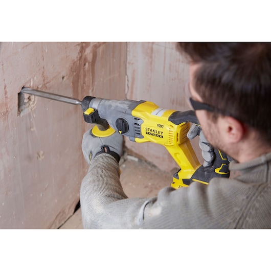 Photo of STANLEY SFMCH900M12 rotary hammer used on plaster wall in construction setting.
