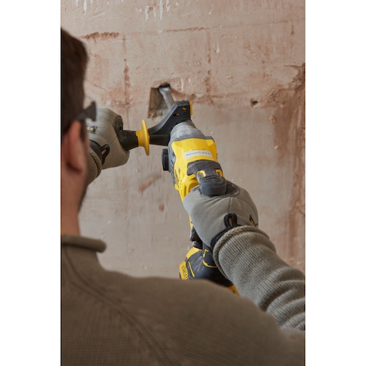 STANLEY SFMCH900M12 rotary hammer tool in use drilling into a plastered wall, close-up from behind.