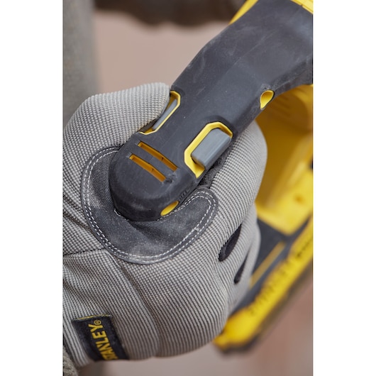 Photo of a gloved hand gripping the handle of a STANLEY SFMCH900M12 power tool, showing the trigger area.