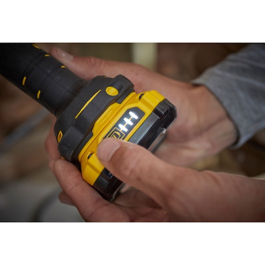 STANLEY SFMCL020B yellow and black tool battery with LED indicator held in hand, close-up photography.