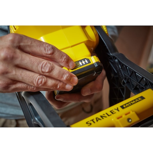 Photo of STANLEY SFMCL030B yellow tool with FATMAX label, close-up of hands adjusting battery.