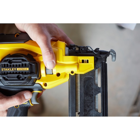 Photo of STANLEY SFMCN616D2K nail gun, close-up of yellow and black body held by hand.