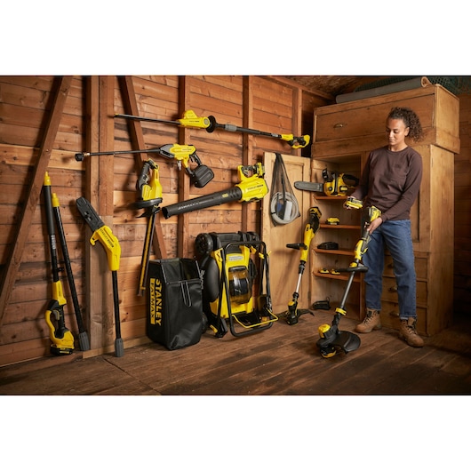 Photo of STANLEY SFMCPS620B cordless outdoor power tools displayed in a wooden shed, with accessories and storage bag.