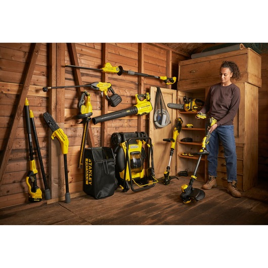 STANLEY SFMCPS620M1 garden power tool kit displayed with tools hung and stored in wooden shed.