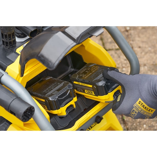 STANLEY SFMCPW1500B battery compartment close-up with gloved hand inserting yellow and black lithium-ion battery.