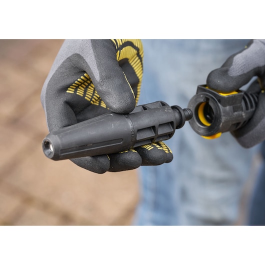 STANLEY SFMCPW1500B nozzle attachment close-up, black and yellow, held by gloved hands outdoors.